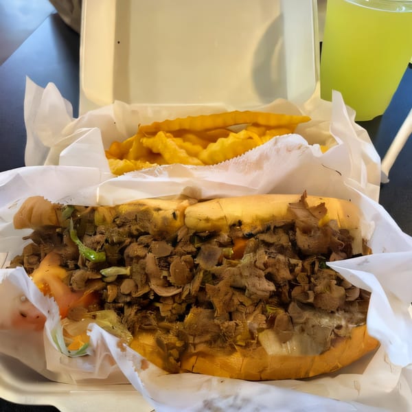 Philly Boyz cheesesteak with fries and a drink in a takeout container.