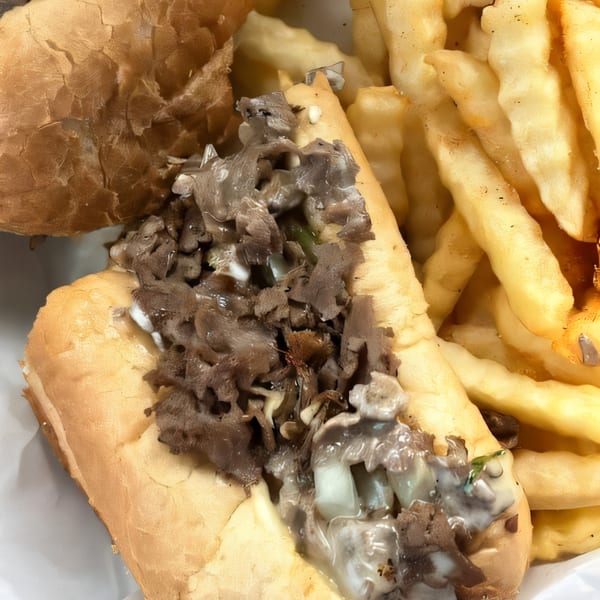 Philly Boyz cheesesteak with melted cheese and steak, served alongside crinkle-cut fries.