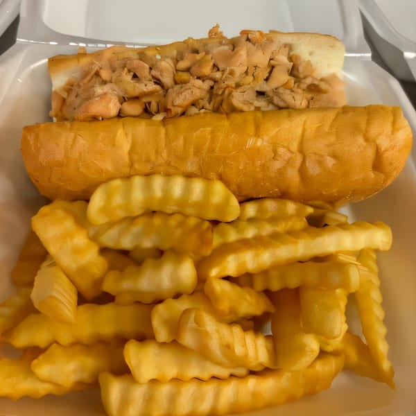A Philly Boyz chicken cheesesteak with crinkle-cut fries in a white takeout container.